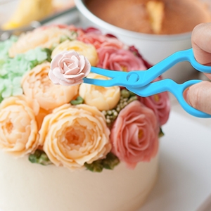 a hand is cutting a flower on a cake.