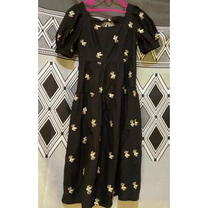 Gen black dress with white and yellow floral embroidery and short puff sleeves.